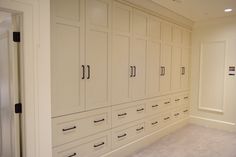 an empty room with white cabinets and drawers