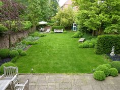 a garden with green grass, bushes and benches