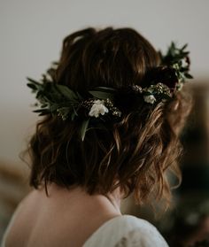 a woman with flowers in her hair wearing a flower crown on her head and looking off into the distance