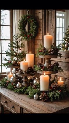 candles are arranged on a table with pine cones and greenery