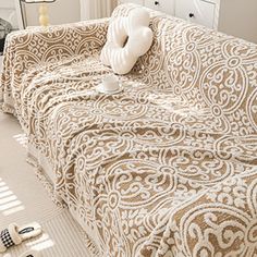 a living room with a couch covered in a brown and white patterned blanket next to a window