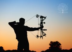 the silhouette of a man holding a bow and arrow in front of an orange sky