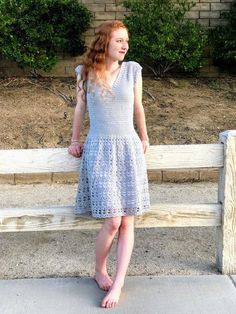 a woman standing next to a wooden fence