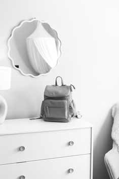 a white dresser with a backpack on top of it