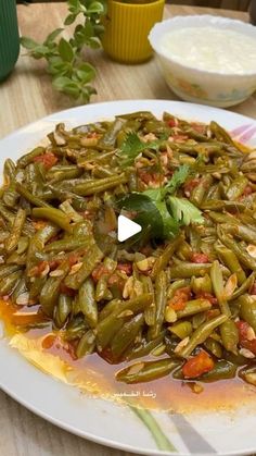 a white plate topped with green beans covered in sauce