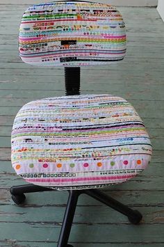 an office chair covered in colorful fabric sitting on top of a wooden floor