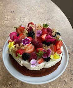 a cake with fruit on it sitting on top of a white plate next to a table