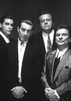 four men in suits and ties posing for the camera