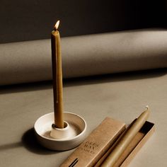 two candles sitting on top of a table next to an empty box and some chopsticks