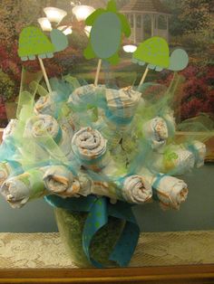 a vase filled with rolled up cupcakes on top of a table next to a painting