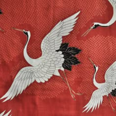 two white cranes on red fabric with black accents