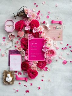 the contents of a pink wedding suite laid out on a white surface with rose petals