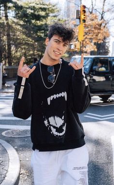 a young man standing in the middle of a crosswalk with his hands up and one hand raised