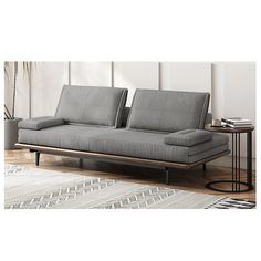 a gray couch sitting on top of a wooden floor next to a table and rug