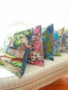 a bunch of pillows sitting on top of a couch in front of a white window