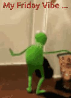 a green alien standing on top of a wooden floor