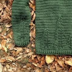 a green knitted sweater laying on top of leaves