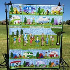 a quilt is displayed in the grass with people and vehicles on it's sides