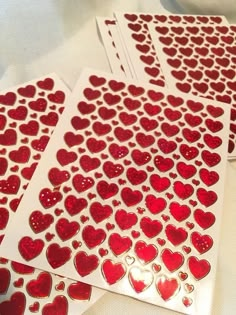 four red heart stickers on white paper next to each other with hearts cut out of them