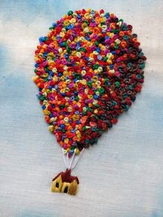 a colorful hot air balloon with a house on it's side and beads all over the bottom