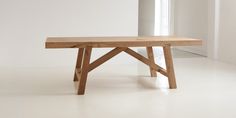 a wooden bench sitting on top of a white floor next to an open window in a room