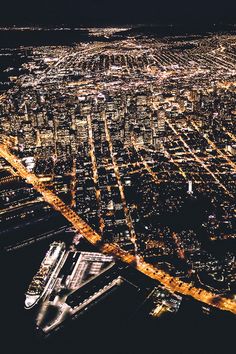 an aerial view of a city at night with lots of lights on the buildings and streets