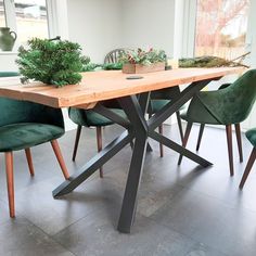 a wooden table with green chairs and potted plants on the top, in front of a window