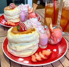 two red plates topped with desserts on top of a wooden table next to drinks