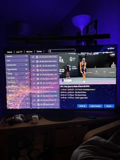 a flat screen tv sitting on top of a wooden table in front of a purple light