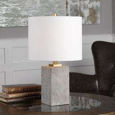 a table lamp sitting on top of a wooden table next to a book and chair