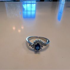 a ring sitting on top of a table with a blue stone in it's center