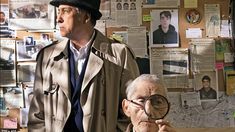 an older man looking through a magnifying glass next to a younger man in a trench coat