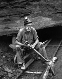 a man sitting in front of a cave with a shovel