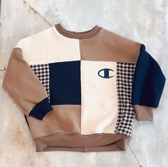 a brown and blue sweater with an eye on it sitting on the floor next to a wall