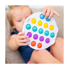 a baby is holding a toy with colored dots on it