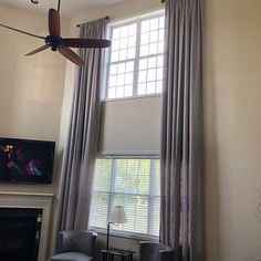 a living room with a ceiling fan and two chairs in front of a window that is open