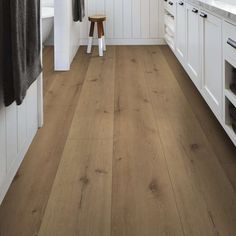 a kitchen with white cabinets and wood flooring on the walls, along with a wooden stool