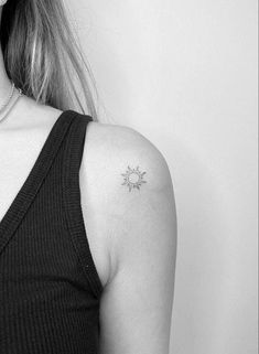 a black and white photo of a woman with a small sun tattoo on her left shoulder