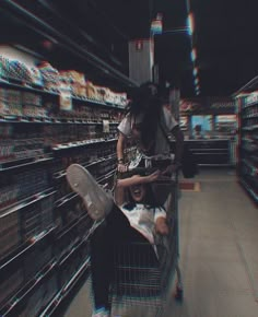 two people sitting in a shopping cart at a grocery store while another person is on the phone