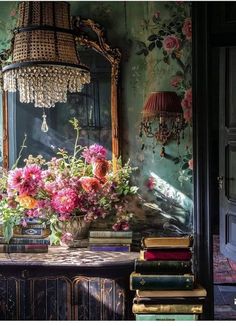 a table topped with lots of pink flowers next to a mirror and books on top of it