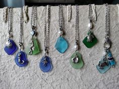 six different colored sea glass necklaces hanging on a wall