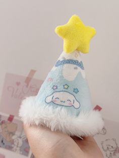 a hand holding a small stuffed animal with a star on it's hat,