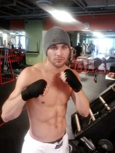 a shirtless man wearing boxing gloves and a beanie is posing for the camera