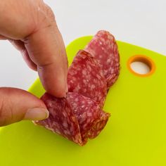 a person is cutting up some meat on a green cutting board