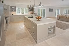 a large kitchen with an island in the middle and stainless steel appliances on both sides