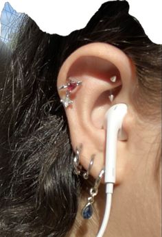 a woman with ear piercings is looking at the side of her ear and has an electric cord attached to it