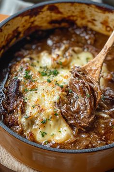 a pot filled with meat and gravy on top of a wooden table