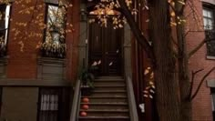 an apartment building with stairs leading up to the front door and pumpkins on the steps