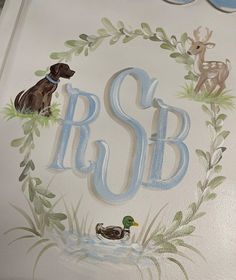 a painted wall with the letter s and two ducks in front of an animal wreath