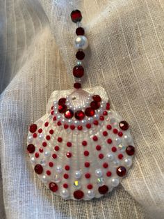 a beaded necklace with red and white beads on it's end, sitting on a piece of cloth